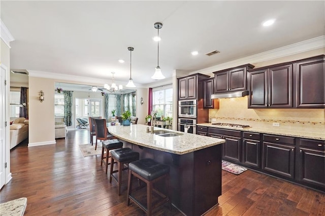 915 Elmsbrook Ln, Alpharetta, GA 30004 - kitchen with a chandelier, crown molding, a breakfast bar, under cabinet range hood, and light stone counters