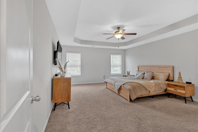 bedroom with a raised ceiling, ceiling fan, and carpet flooring