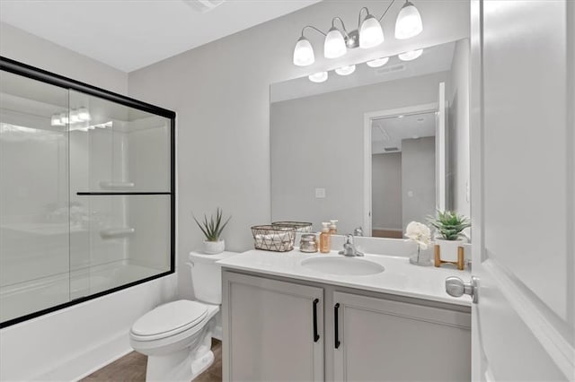 full bathroom featuring vanity, combined bath / shower with glass door, and toilet