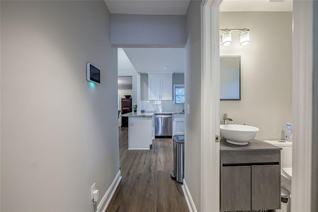 hallway featuring baseboards, a sink, and dark wood-style flooring