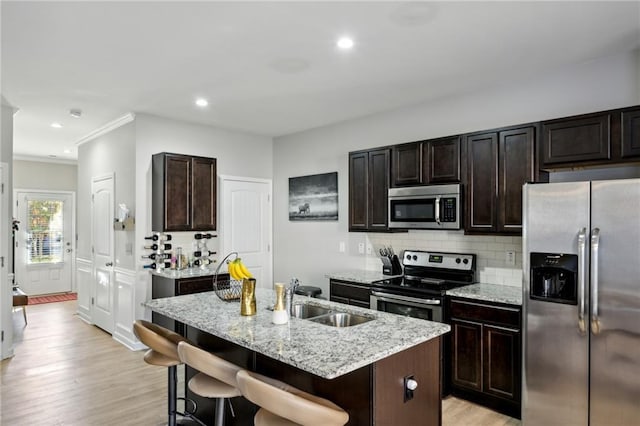 kitchen featuring stainless steel appliances, backsplash, a sink, and light wood-style floors