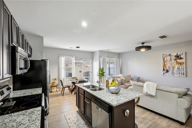 kitchen with light wood finished floors, visible vents, appliances with stainless steel finishes, open floor plan, and a sink