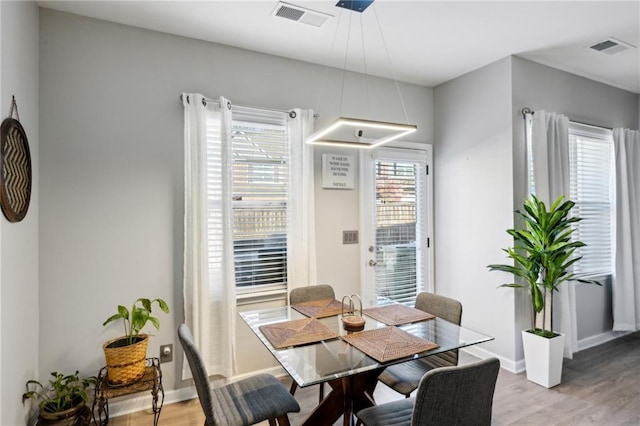 dining room with light wood finished floors, visible vents, and baseboards