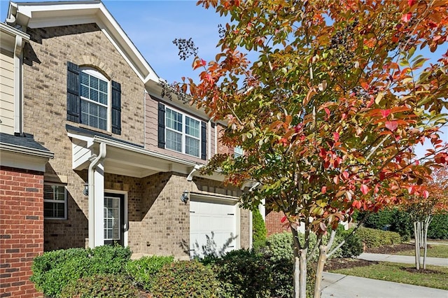 view of property featuring a garage and brick siding