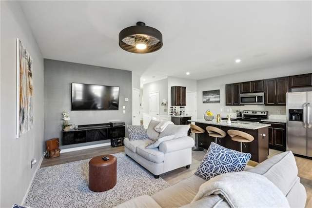 living room featuring baseboards, light wood-style floors, and recessed lighting