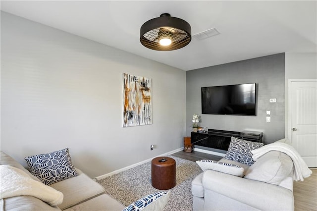 living area featuring visible vents, baseboards, and wood finished floors