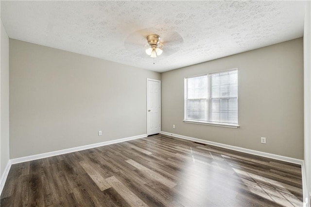 unfurnished room featuring ceiling fan, baseboards, dark wood-style flooring, and a textured ceiling