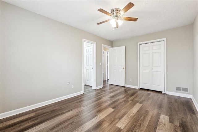 unfurnished bedroom featuring a closet, baseboards, visible vents, and dark wood-style flooring