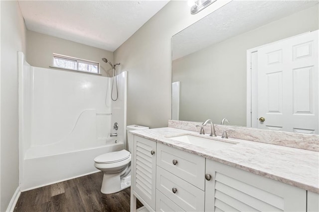 bathroom featuring toilet, a textured ceiling, wood finished floors,  shower combination, and vanity