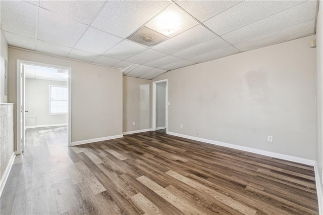 unfurnished room with dark wood-style floors, a paneled ceiling, and baseboards