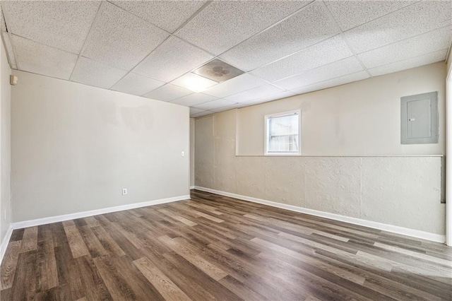 basement with electric panel, wood finished floors, baseboards, and a drop ceiling