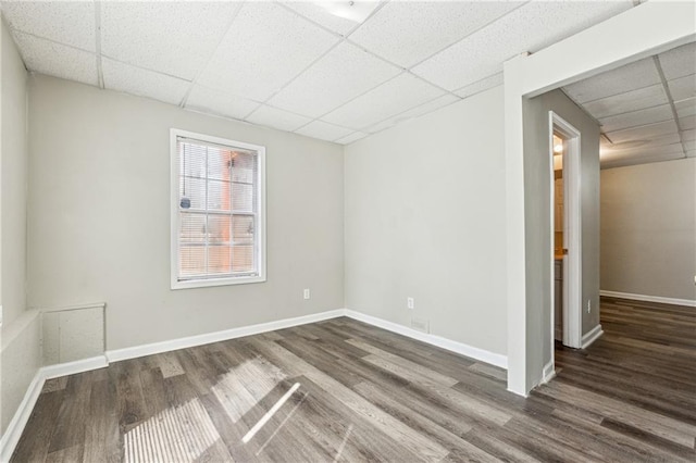 unfurnished room featuring a drop ceiling, baseboards, and wood finished floors