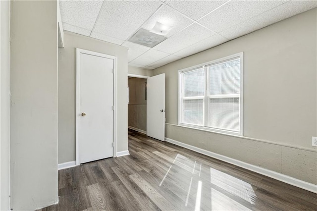 unfurnished room with a drop ceiling, baseboards, and wood finished floors