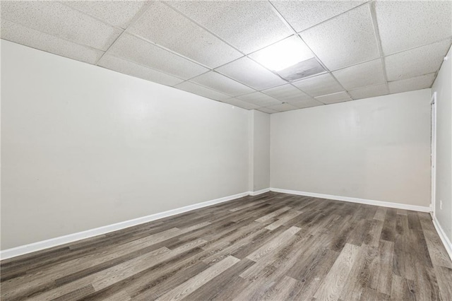 unfurnished room featuring wood finished floors, baseboards, and a paneled ceiling