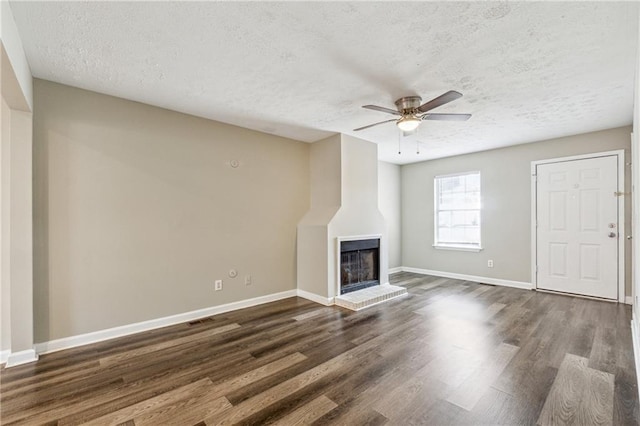 unfurnished living room with a textured ceiling, baseboards, dark wood-type flooring, and ceiling fan