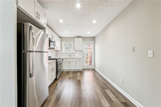 kitchen with stainless steel appliances, baseboards, backsplash, and dark wood finished floors