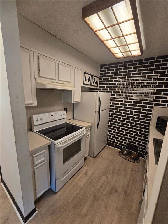 1297 Tree Creek Ct, Clarkston, GA 30021 - kitchen with white appliances, under cabinet range hood, light countertops, white cabinetry, and light wood-style flooring