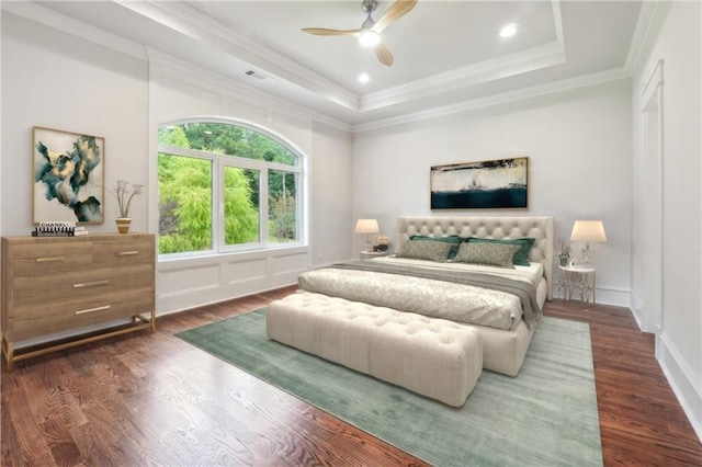 bedroom with dark wood-type flooring, ornamental molding, a raised ceiling, and ceiling fan