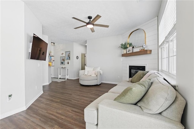 living room featuring baseboards, a large fireplace, ceiling fan, and wood finished floors