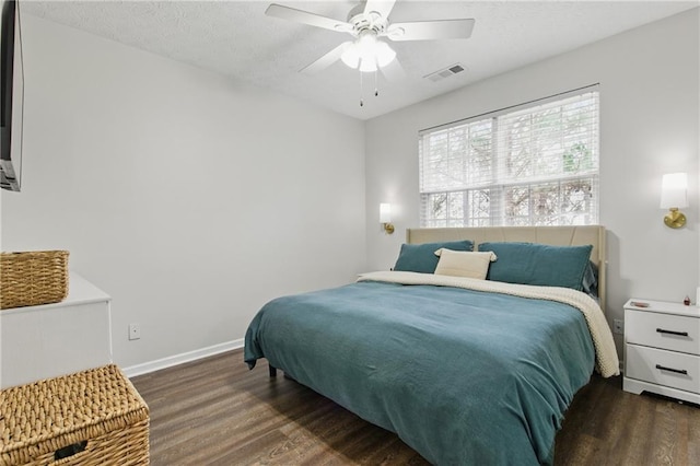 bedroom featuring visible vents, a textured ceiling, baseboards, and wood finished floors