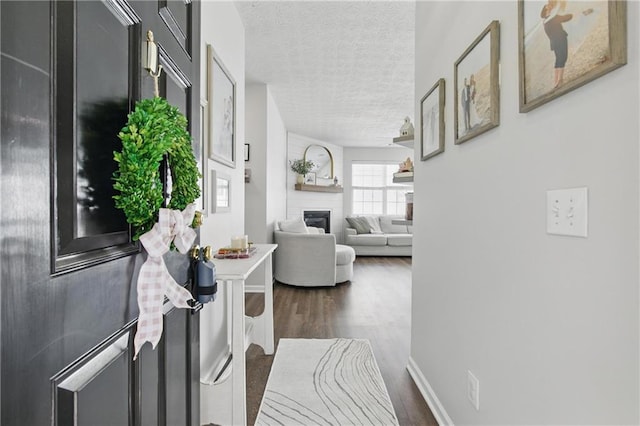 hall with baseboards, dark wood-type flooring, and a textured ceiling