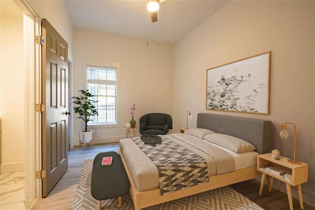 bedroom featuring baseboards, light wood-style flooring, and a ceiling fan