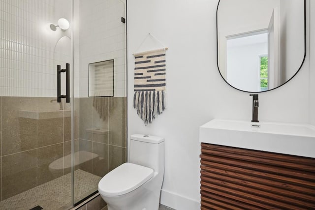 bathroom featuring vanity, a shower with door, and toilet