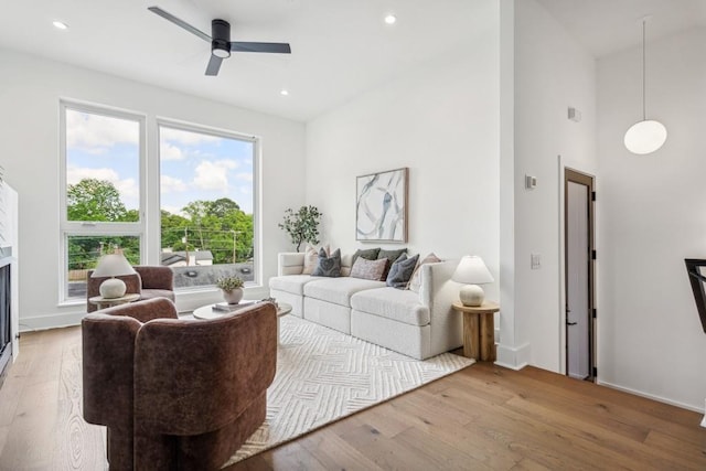 living room featuring ceiling fan, wood-type flooring, and a towering ceiling