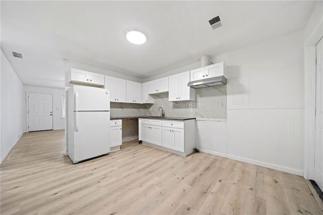 kitchen featuring sink, light hardwood / wood-style flooring, white refrigerator, backsplash, and white cabinets