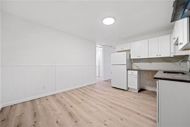 kitchen featuring white cabinets, white fridge, light hardwood / wood-style flooring, and sink