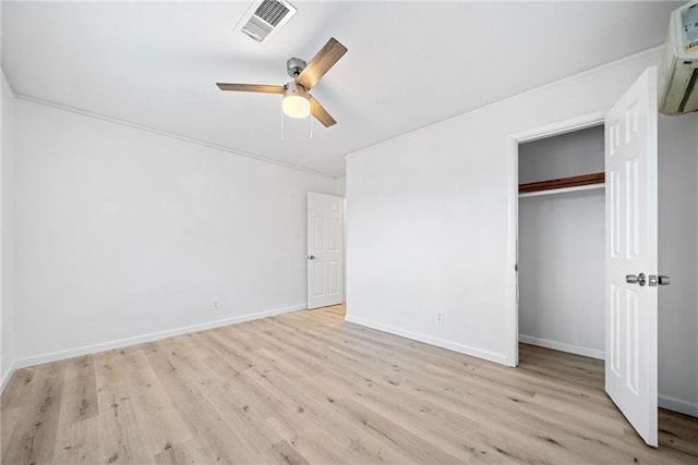 unfurnished bedroom featuring ceiling fan, a wall unit AC, light hardwood / wood-style floors, a closet, and ornamental molding