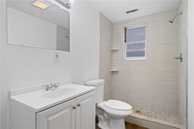 bathroom with tiled shower, vanity, and toilet