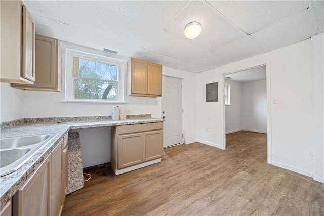 kitchen with a paneled ceiling, electric panel, sink, light hardwood / wood-style flooring, and light brown cabinetry