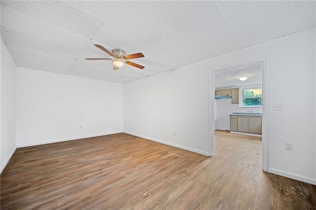 unfurnished room featuring ceiling fan, a drop ceiling, and wood-type flooring