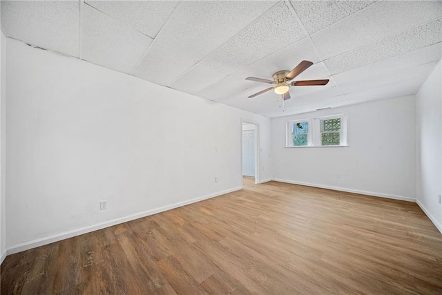 empty room with ceiling fan, a drop ceiling, and wood-type flooring