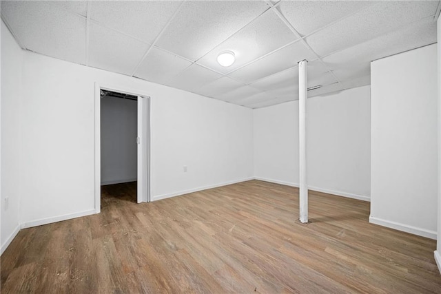 basement featuring a paneled ceiling and wood-type flooring