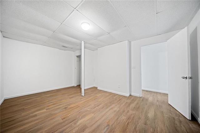 basement with a paneled ceiling and wood-type flooring