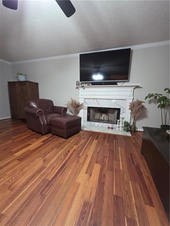 77 Ben W Dr, Cedartown, GA 30125 - living area with a ceiling fan, a fireplace, wood finished floors, a textured ceiling, and crown molding
