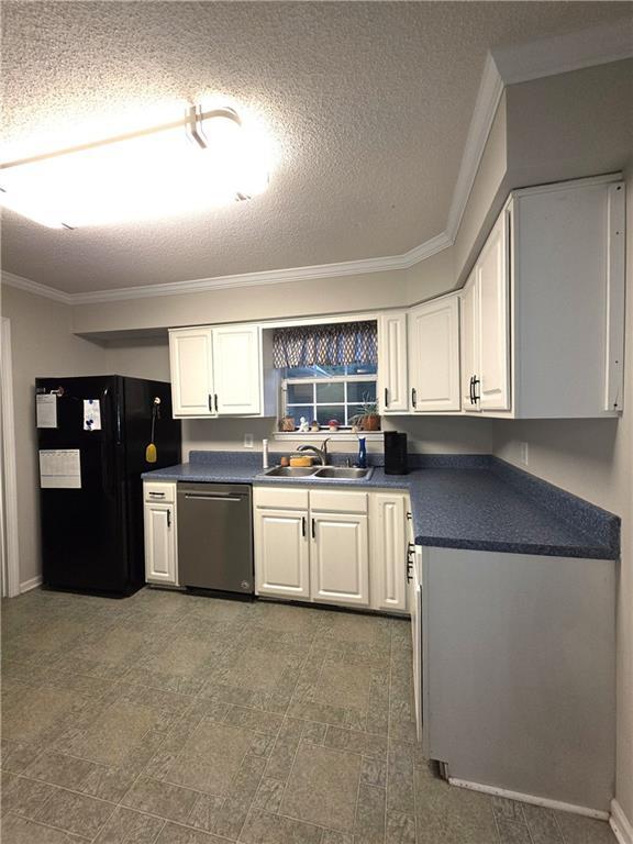 77 Ben W Dr, Cedartown, GA 30125 - kitchen with stainless steel dishwasher, freestanding refrigerator, dark countertops, white cabinetry, and a textured ceiling