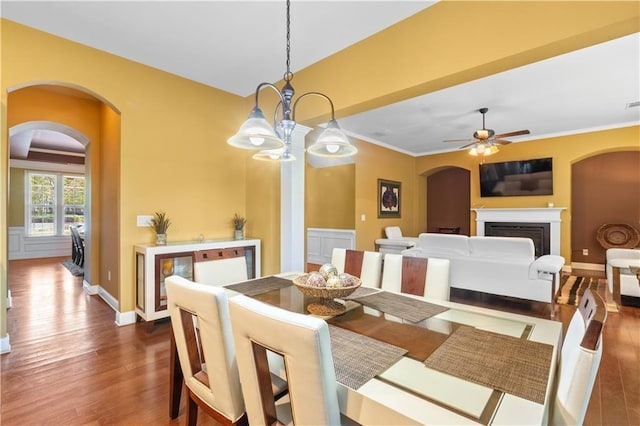 dining area with ceiling fan with notable chandelier, arched walkways, and dark wood finished floors