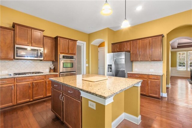 kitchen featuring dark wood-style floors, arched walkways, and stainless steel appliances