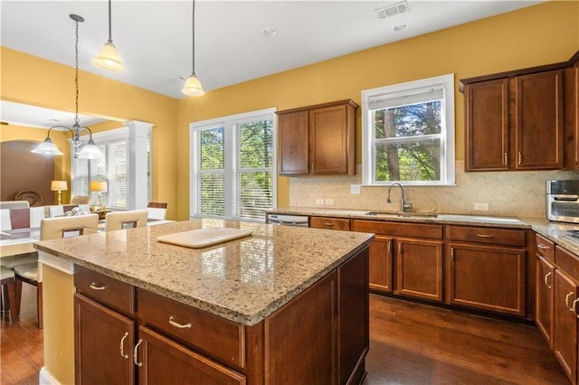 kitchen with visible vents, a center island, a healthy amount of sunlight, dark wood-style flooring, and a sink
