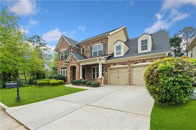 view of front of house featuring driveway, a front yard, a garage, and brick siding
