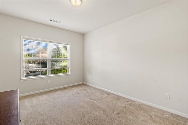 spare room with carpet flooring, visible vents, and baseboards