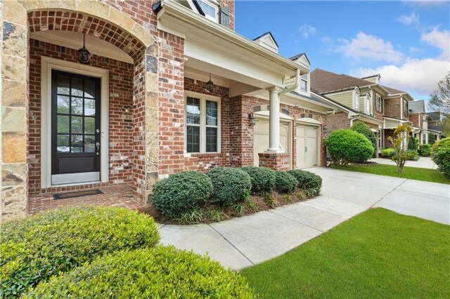 property entrance featuring concrete driveway and brick siding