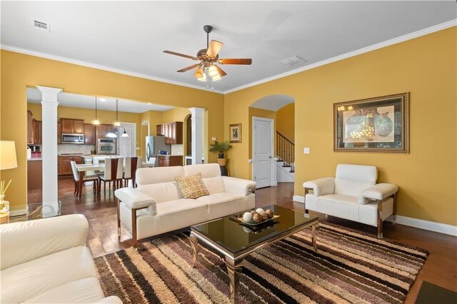 living area featuring a ceiling fan, crown molding, dark wood-type flooring, visible vents, and arched walkways