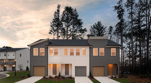 modern home featuring board and batten siding, an attached garage, driveway, and a front yard