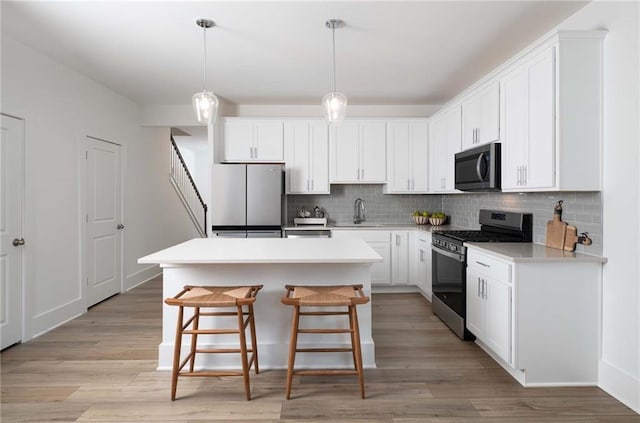 kitchen featuring tasteful backsplash, a kitchen island, stainless steel appliances, and white cabinetry