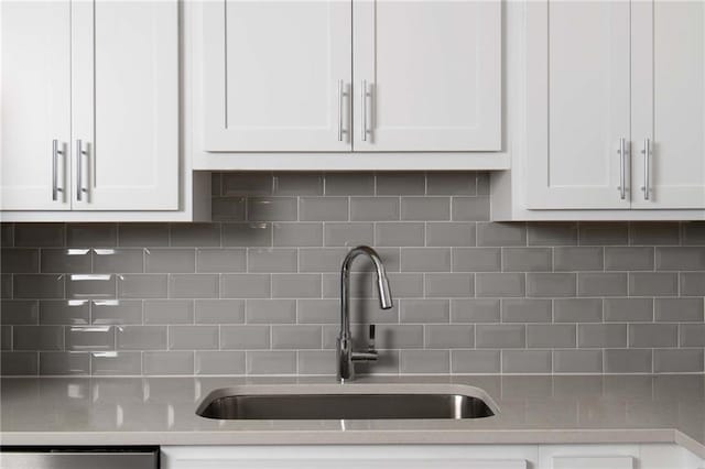 kitchen with a sink, decorative backsplash, white cabinets, and dishwasher