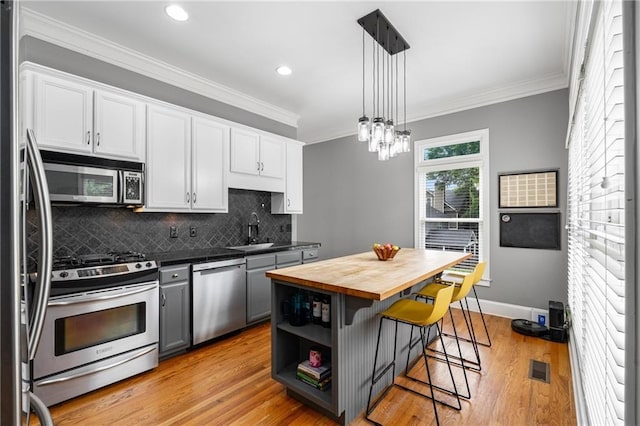 1912 Hosea L Williams Dr NE Unit 1, Atlanta, GA 30317 - kitchen with appliances with stainless steel finishes, wooden counters, a kitchen breakfast bar, a sink, and white cabinetry